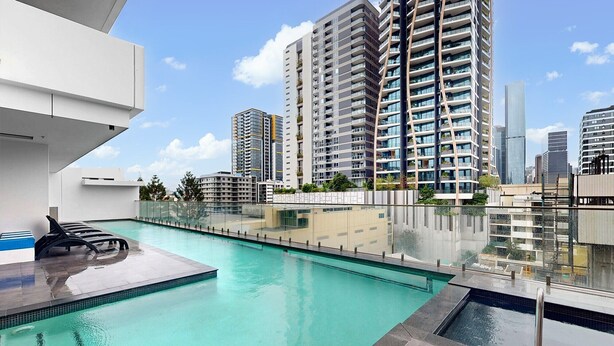 A rooftop pool with clear blue water, surrounded by modern high-rise buildings.