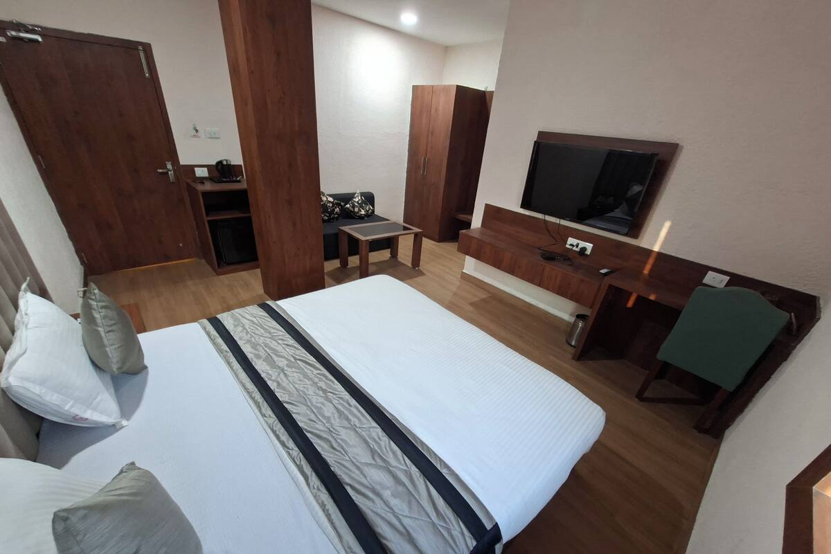 A hotel room with a large bed, a TV, a desk, and a wardrobe.