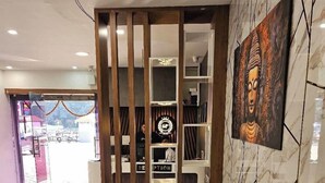 Ένας χώρος υποδοχής με έναν πράσινο καναπέ, έναν πάγκο υποδοχής και ένα άγαλμα του Βούδα τοποθετημένο στον τοίχο.