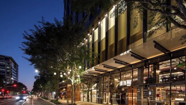 A modern building with a glass facade and a bench outside.