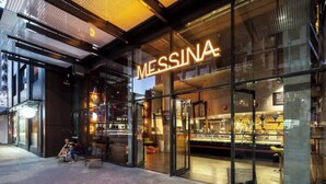 A modern storefront with a glass facade and a neon sign reading "MESSINA."