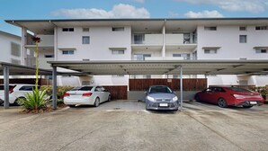 Un área de estacionamiento con tres autos bajo una estructura cubierta.
