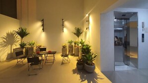 A modern interior with a dining area, potted plants, and a glass elevator. - The Chilling'N Homestay (Hanoi)