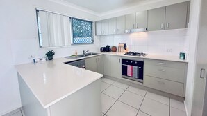 Una cocina moderna con armarios blancos, una isla grande, horno empotrado y ventana con vistas.