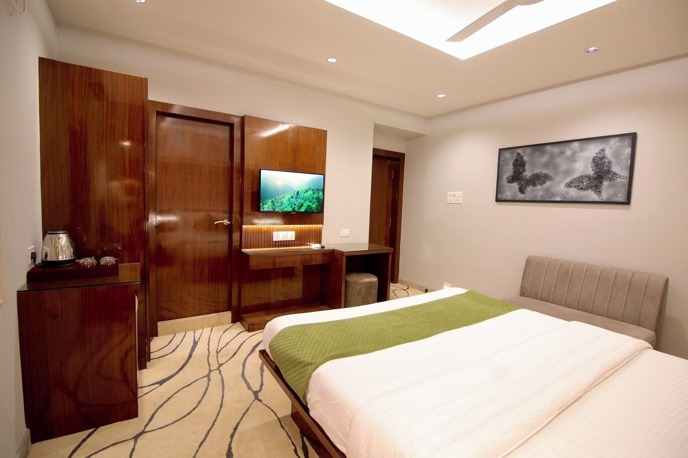 Habitación de hotel con cama, escritorio, televisor y un cuadro en la pared.