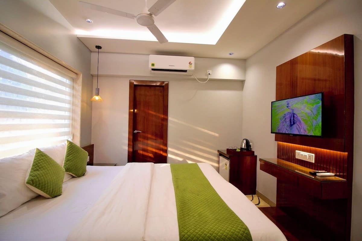A hotel room with a bed, a TV, a desk, and a wardrobe.