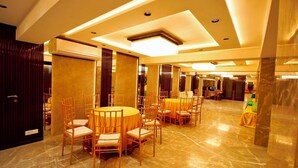 A spacious, well-lit dining area with marble flooring and wooden furniture. - Evara By Meraki Inn (Kolkata)