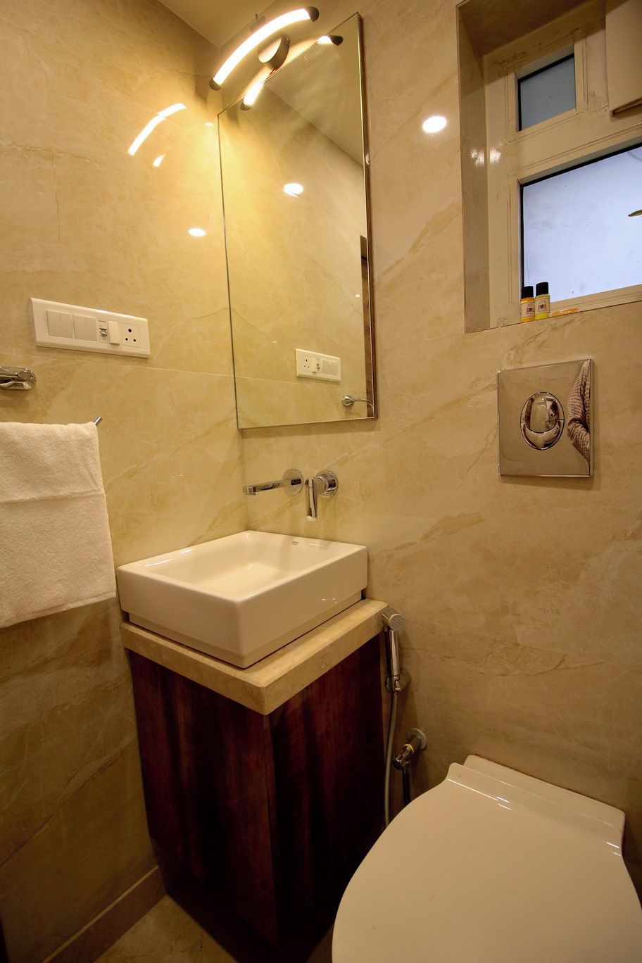 A bathroom with a white sink, mirror, and toilet. There is a towel rack and a towel hanging on it.