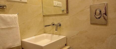 A bathroom with a white sink, mirror, and toilet. There is a towel rack and a towel hanging on it.