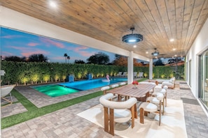 Un patio exterior con piscina, zona de estar y vista al atardecer.