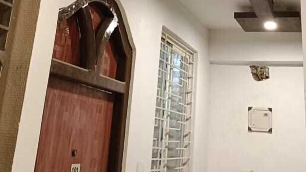 Une pièce dotée d’un éclairage encastré au plafond, d’une porte en bois et d’une fenêtre avec des barreaux en métal.