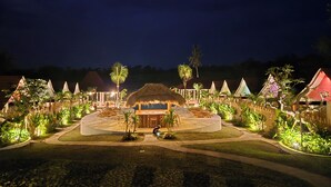 A resort with thatched-roof huts, a central pool area, and surrounding lush greenery. - UNITED COLORS OF BALI NATURE (Tibubeneng)