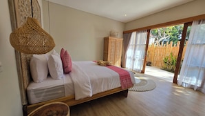 A bedroom with a bed, a wooden cabinet, a woven basket, and a view of the outdoors. - UNITED COLORS OF BALI NATURE (Tibubeneng)