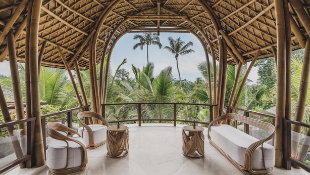 A bamboo-framed room with two white cushioned sofas and round tables, overlooking lush greenery and palm trees. - Maar Resort Ubud by Ini Vie Hospitality (Payangan)