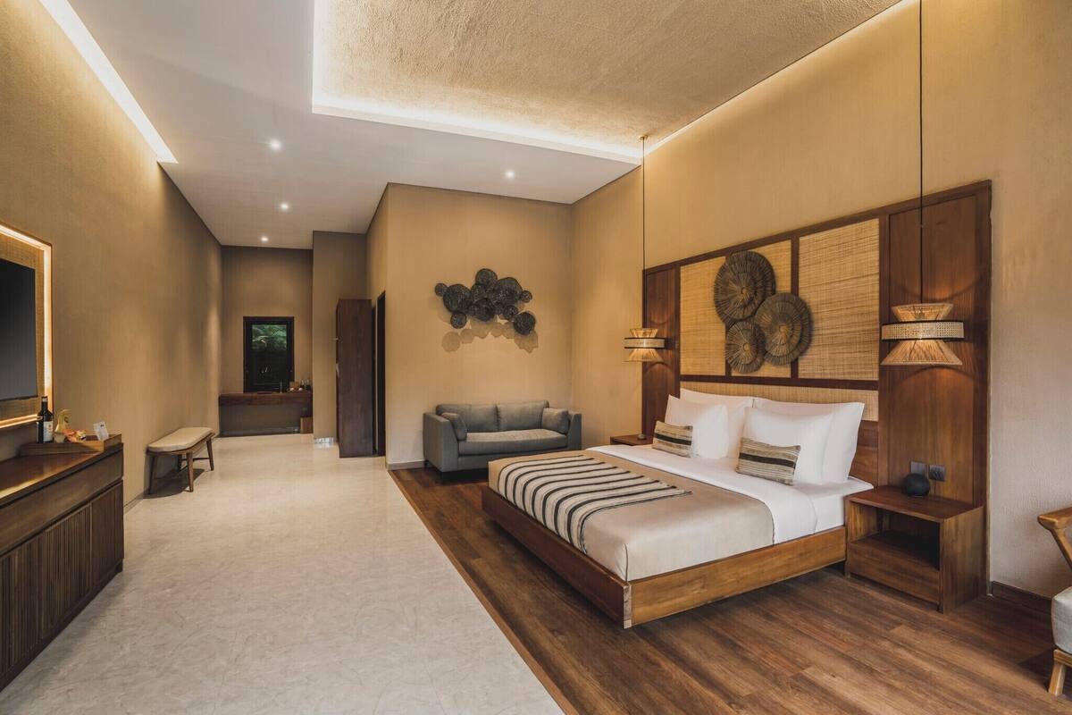 A bedroom with a bed, bedside tables, a sofa, a desk, and a mirror.