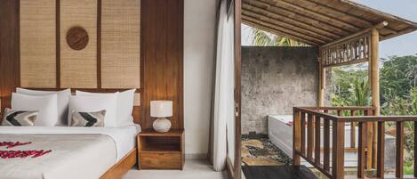 A bedroom with a wooden headboard, a bed with white linens, a nightstand with a lamp, and a view of a balcony with a wooden railing.