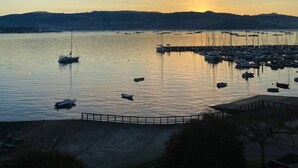 A marina with boats docked, calm water, and a sunset in the background.