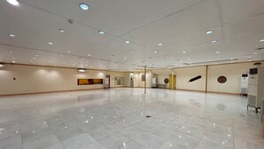 A spacious, well-lit room with a polished marble floor, recessed ceiling lights, and a few pieces of wall art.