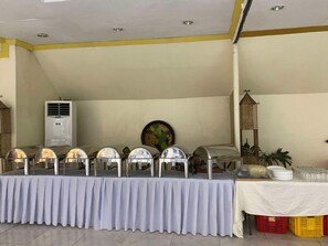 A buffet setup with multiple food service stations, a ceiling fan, and a decorative wall piece. - Flores De Musa by Curv Hotels (Puerto Princesa)