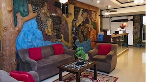 A modern lobby with a large wall mural, two sofas, a coffee table, and a reception desk.