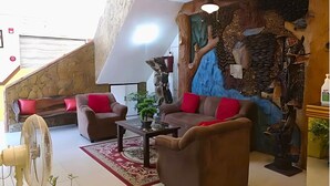 A modern living room with a stone wall, a wooden sculpture, and a ceiling fan.