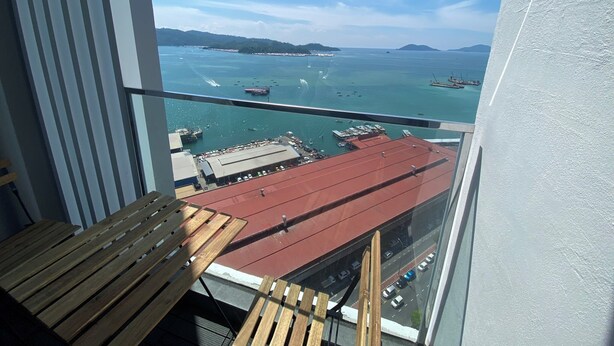 A balcony with a view of a harbor, boats, and distant islands.
