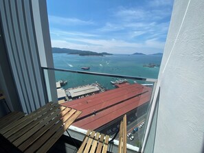 A balcony with a view of a harbor, boats, and distant islands.