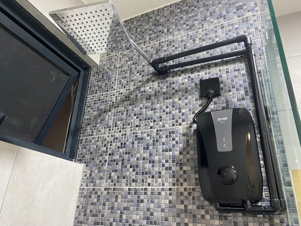A bathroom with a tiled backsplash, a showerhead, and a water heater unit.