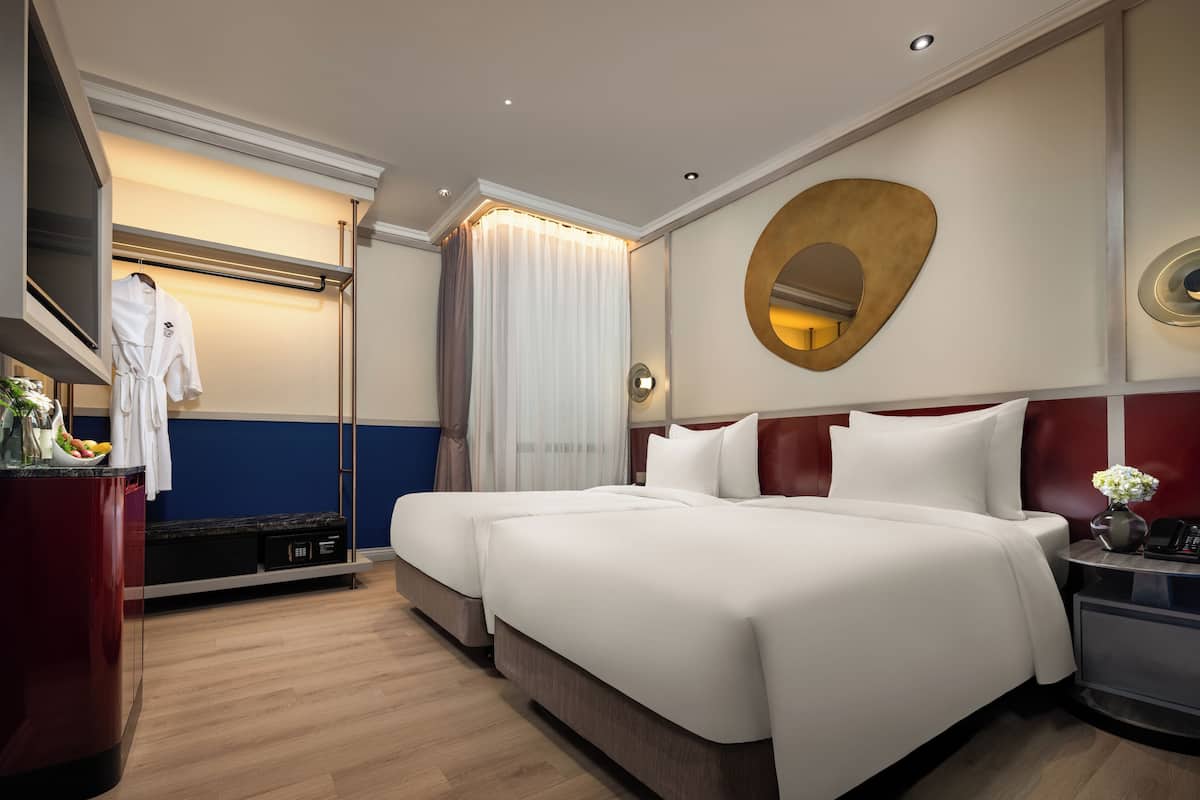 A hotel room with a large bed, a bedside table with a lamp, a mirror, and a wardrobe.