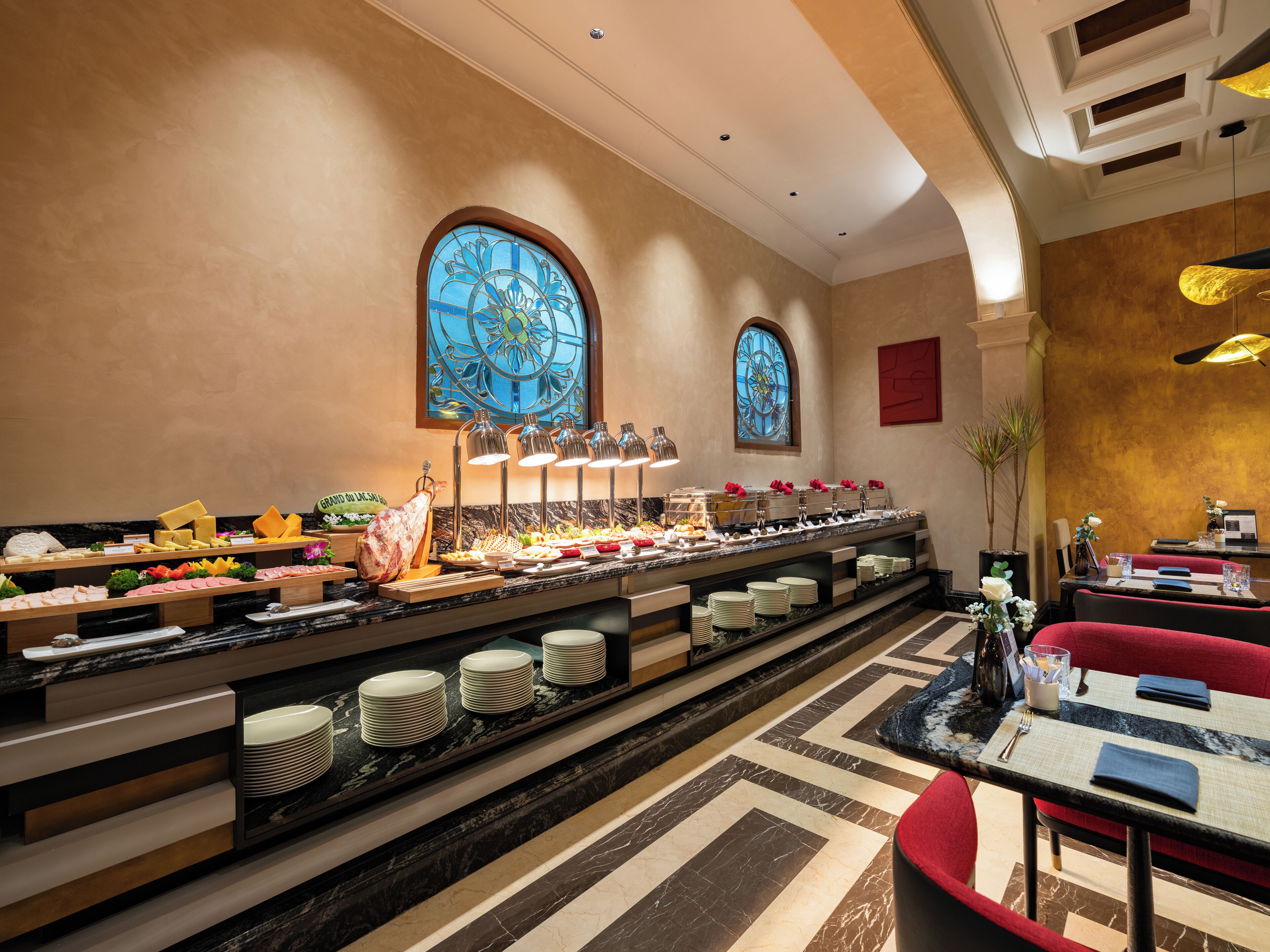 A buffet area with various food items and a seating area with tables and chairs.