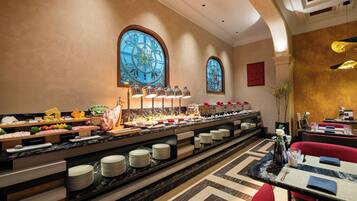 A buffet area with various food items and a seating area with tables and chairs.