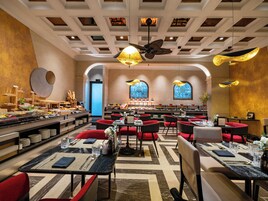 Un'ampia sala da pranzo con diversi tavoli e sedie, una ventola a soffitto e un buffet con una varietà di cibi.