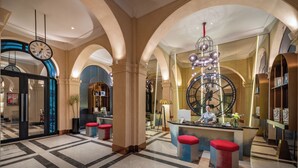 A spacious lobby with a large clock, red and blue seating, and a central reception desk. - GRAND HOTEL du LAC Boutique Saigon (Ho Chi Minh City)