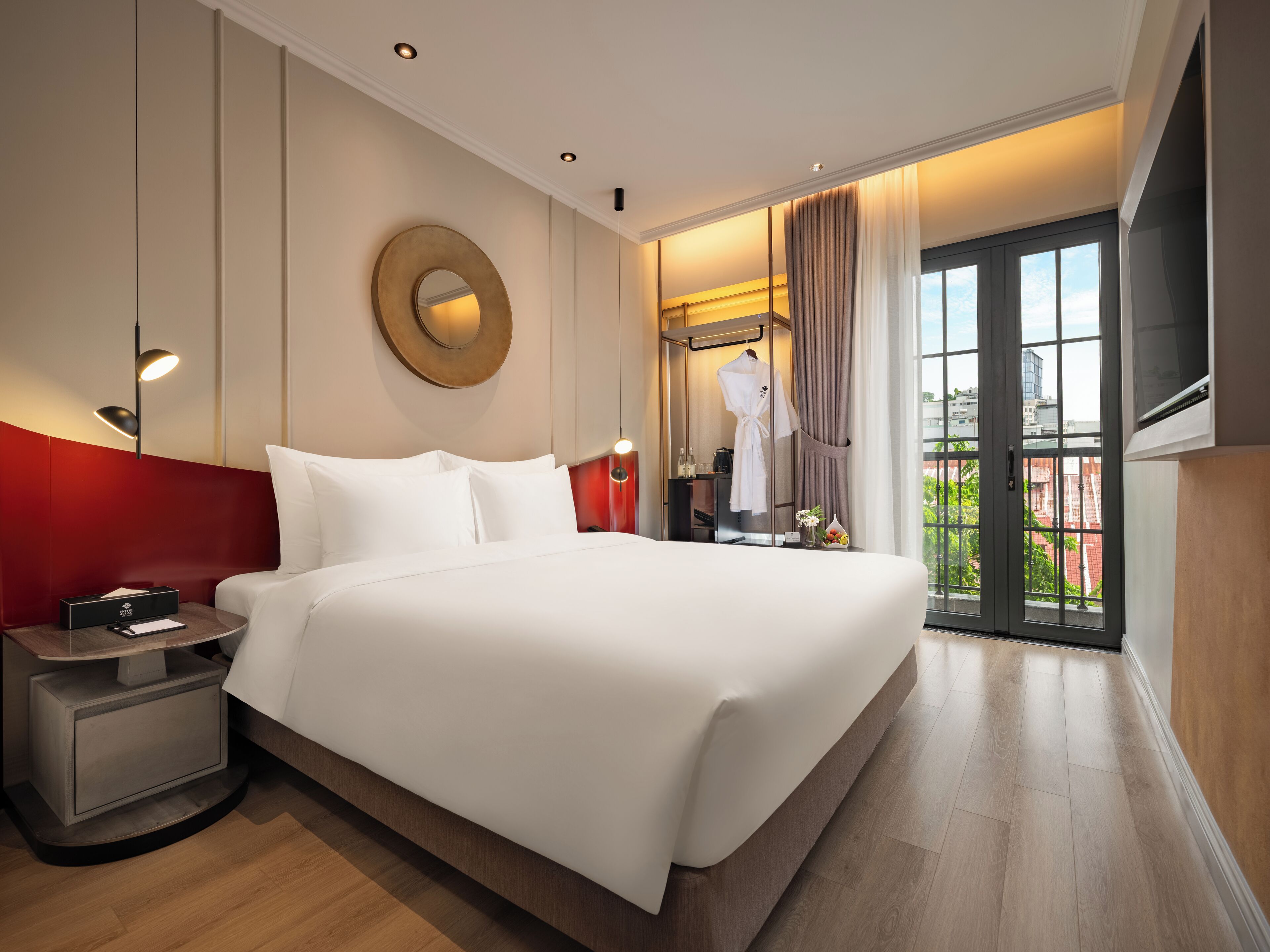 Une chambre d’hôtel moderne dotée d’un grand lit, d’une table de chevet, d’une télévision et d’une grande fenêtre avec des rideaux, offrant une vue sur la ville.