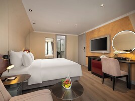 A modern hotel room with a bed, desk, chair, and a round mirror.