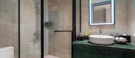 A modern bathroom with a glass-enclosed shower, a white sink, and a green countertop.