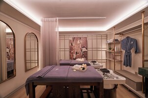 Un cuarto de spa con dos camillas de masaje, un lavamanos y un perchero para batas.