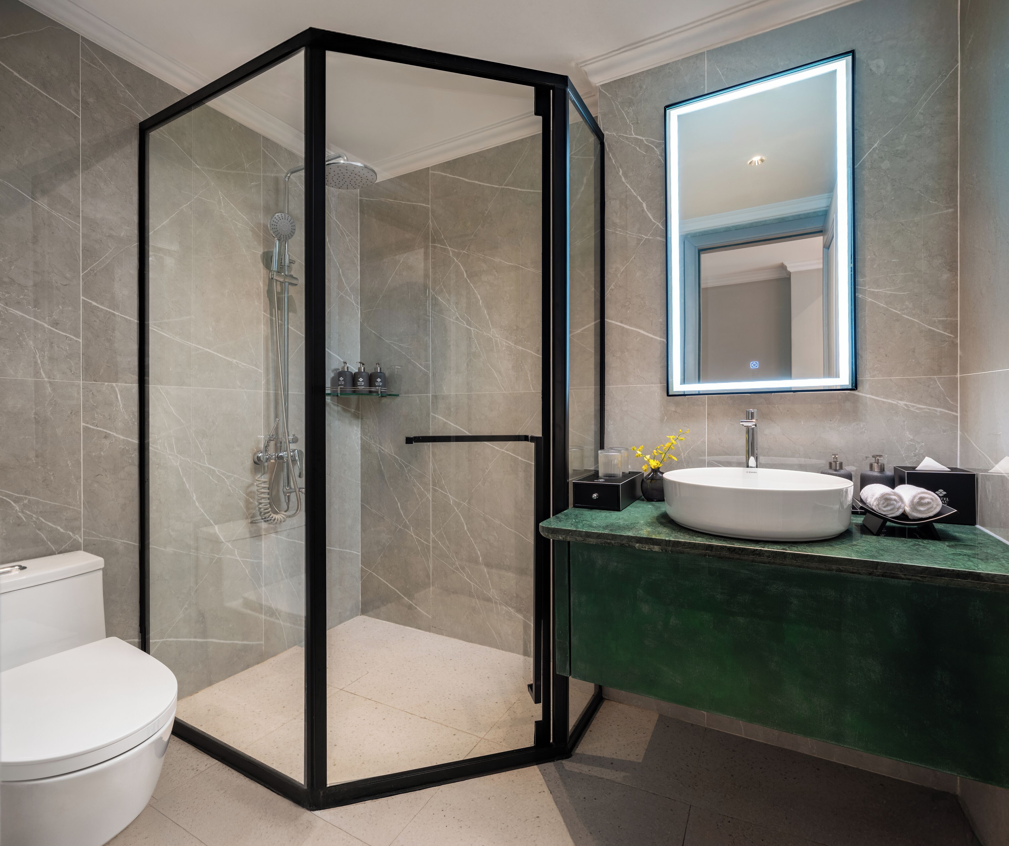 A modern bathroom with a glass-enclosed shower, a white sink, and a green countertop.