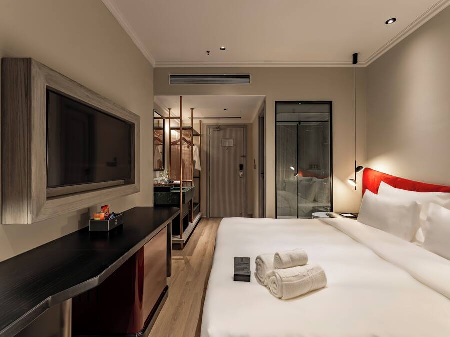 A hotel room with a bed, a TV, a desk, and a wardrobe.