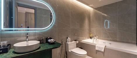 A modern bathroom with two sinks, a toilet, and a bathtub.