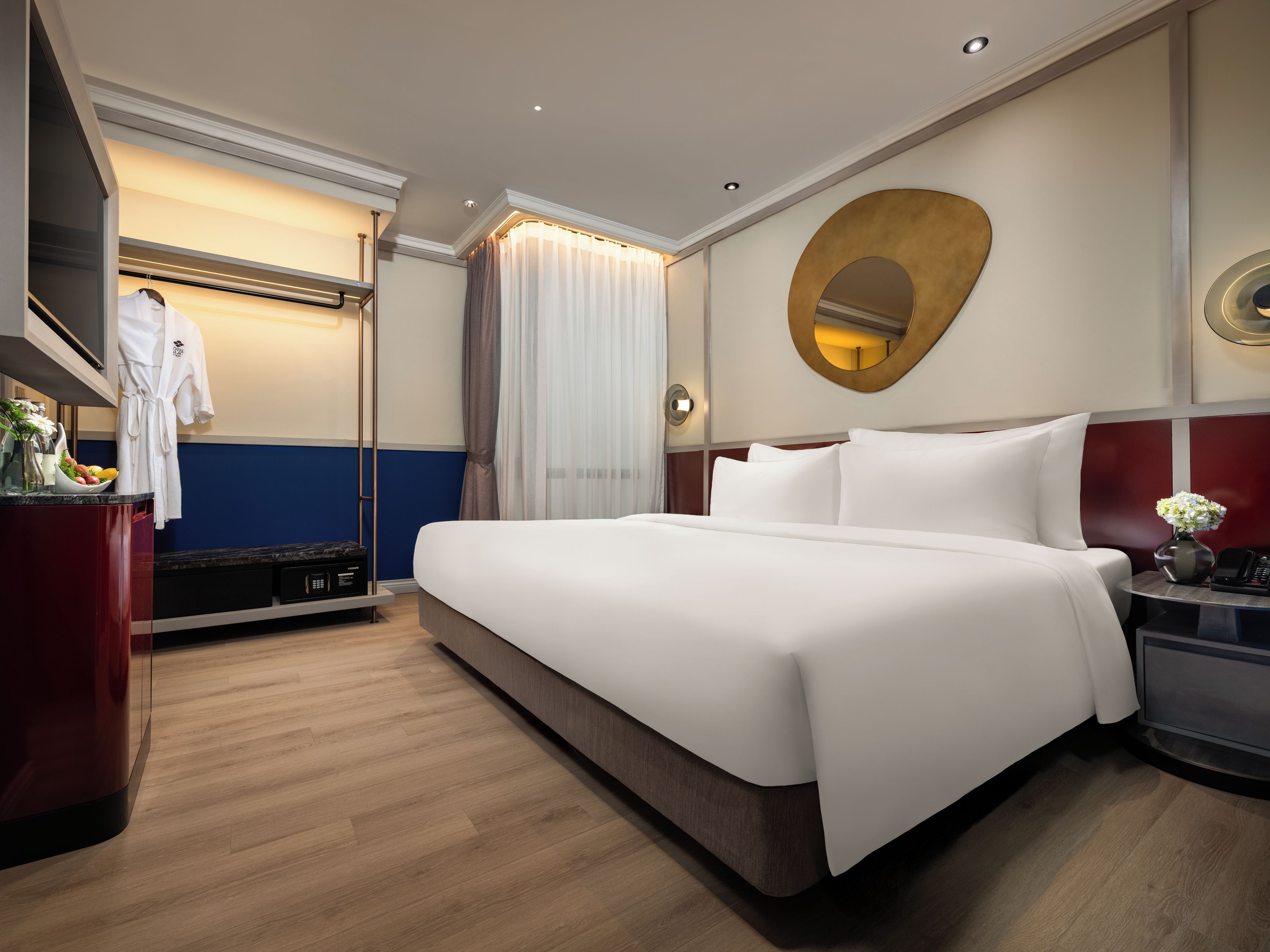 Quarto de hotel com uma cama grande, mesa de cabeceira com um vaso, espelho e guarda-roupa.