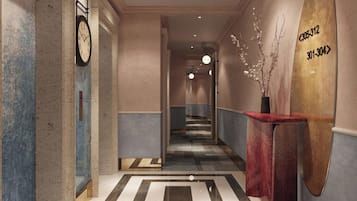 A hotel lobby with a clock, directional signs, and a reception desk.