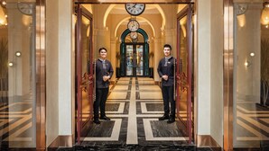 A grand entrance with a marble floor, a large chandelier, and two uniformed staff members standing at the doors. - GRAND HOTEL du LAC Boutique Saigon (Ho Chi Minh City)