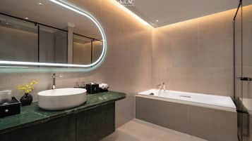 A modern bathroom with a large mirror, two sinks, and a bathtub.
