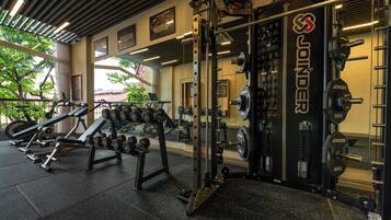A gym with weightlifting equipment, mirrors, and a view of the outdoors.