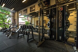 A gym with weightlifting equipment, mirrors, and a view of the outdoors.