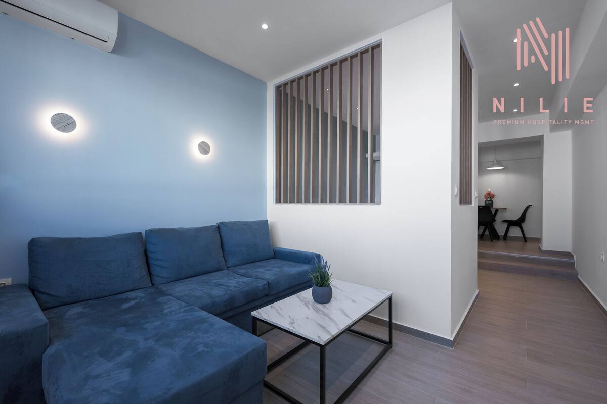 Ein stilvolles Wohnzimmer mit einem blauen Sofa, einem Marmortisch und einer Topfpflanze.