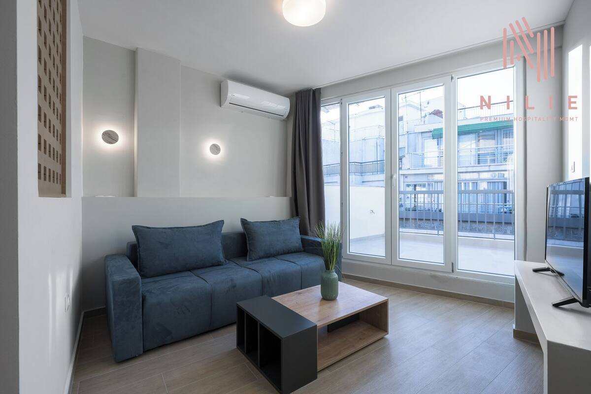 Ein modernes Wohnzimmer mit grauem Sofa, Couchtisch und Fernseher auf einem Schrank.