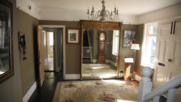 A hallway with a large mirror, a chandelier, a wooden floor, and a staircase. - House Sleeps 9-garden-pool-bbq-patio-parking (Maidstone)