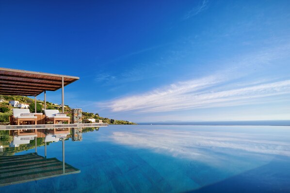 A waterfront property with a clear pool, wooden deck, and a view of the sea. - Mythic Villa (Sifnos)